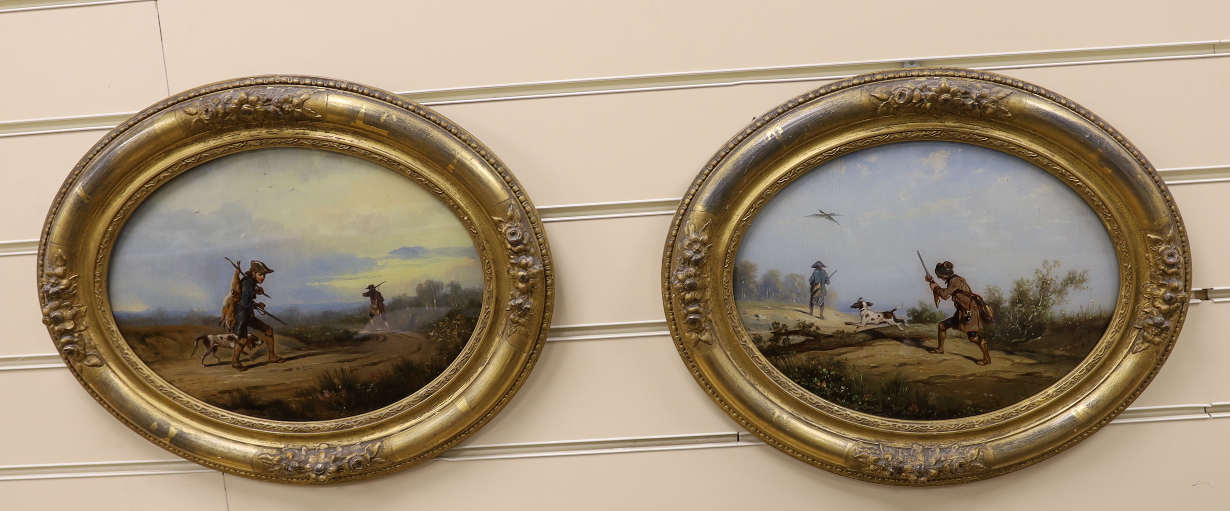 A pair of 19th century reverse painted oval framed sporting scenes, figures shooting along a pathway, 23 x 31cm